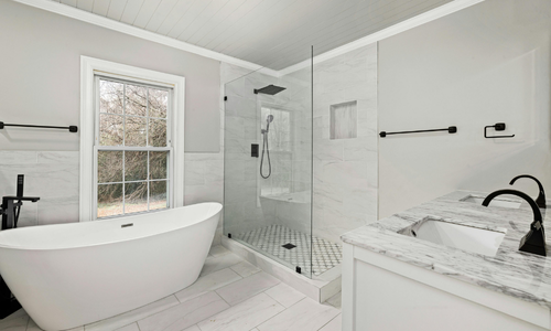 Modern bathroom renovation featuring a freestanding tub, glass walk-in shower, marble countertop, and matte black fixtures.